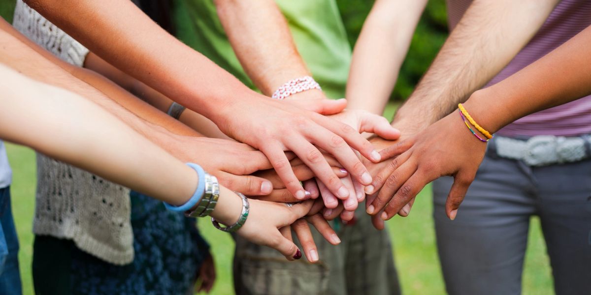 Diverse group joining hands in unity outdoors